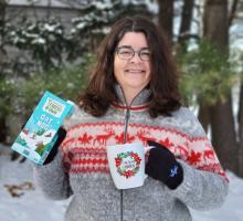 Oat Newsletter editor Charlene Wight holds a carton of "Oat Nog" and a mug that says "Warm Wishes"